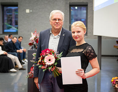 WIR-Dekan Prof. Christian Müller mit einer Absolventin nach der Überreichnung von Blumen und Urkunde