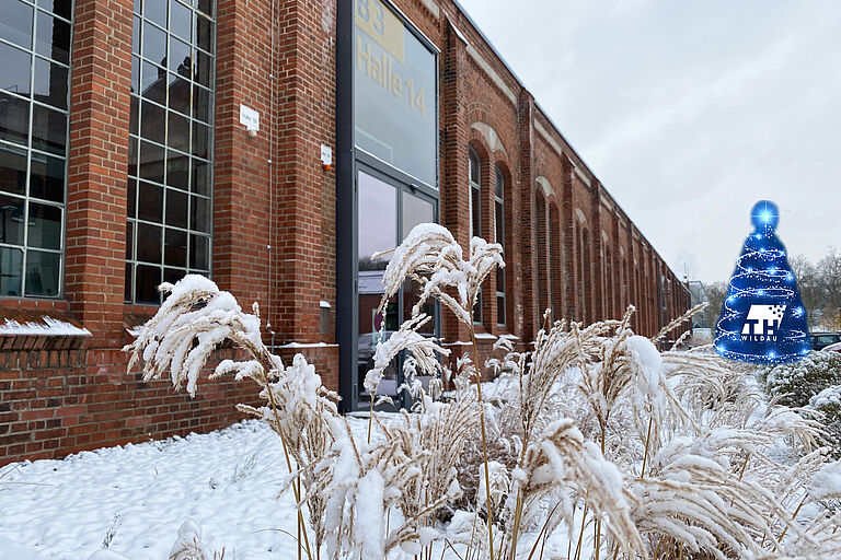 Schneebedeckter Campus mit rotem Backsteingebäude im Hintergrund