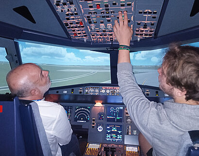 Zwei Personen sitzen im Cockpit eines Flugsimulators