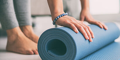 Frau breitet Yoga-Matte auf dem Boden aus