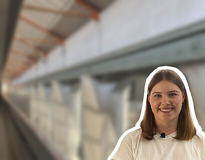 Junge Frau in weißem Shirt mit historischer Hallenkonstruktion im Hintergrund