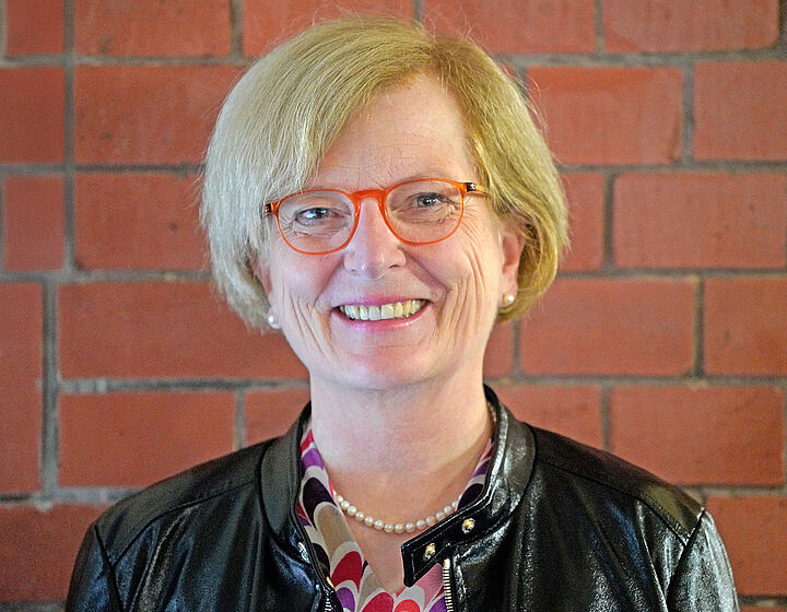 Prof. Ulrike Tippe Portraitbild von Prof. Ulrike Tippe vor einer roten Backsteinwand