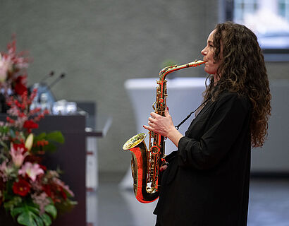 Schwarz gekleidete Frau mit langen Haaren spielt Saxophon