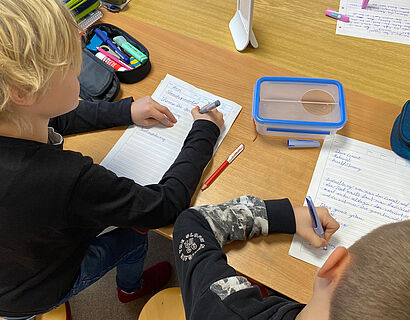 zwei Kinder schreiben Protokolle zu den durchgeführten Versuchen