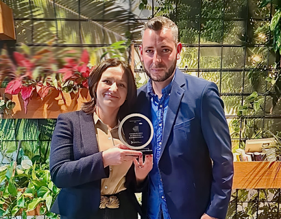 Auszeichnung Zwei Personen vor einer Pflanzenwand mit einem Preis in der Hand