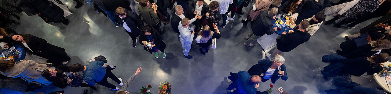 Blick von oben auf das mit vielen Personen gefüllte Foyer von Halle 17 bei der feierlichen Verabschiedung 2024