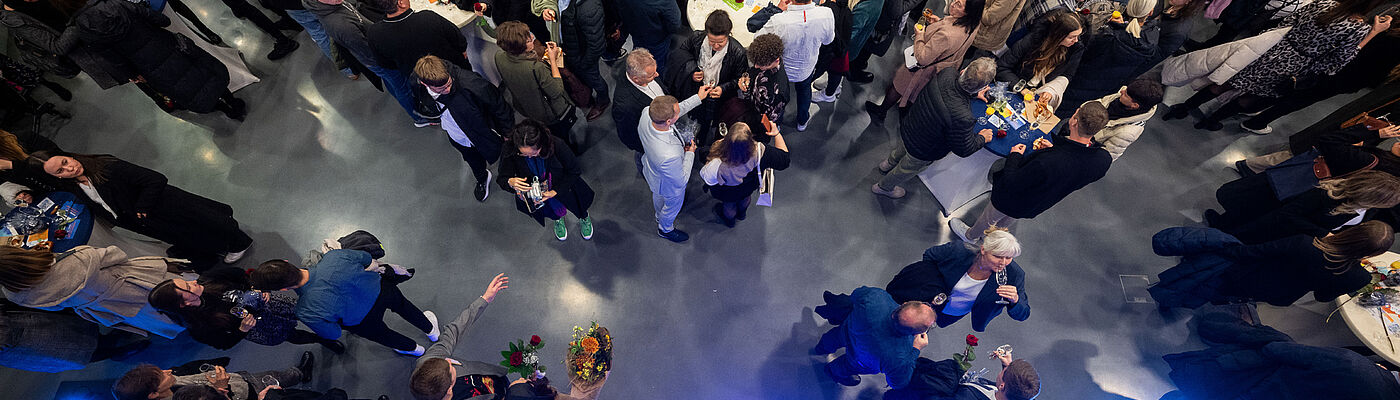 Blick von oben auf das mit vielen Personen gefüllte Foyer von Halle 17 bei der feierlichen Verabschiedung 2024