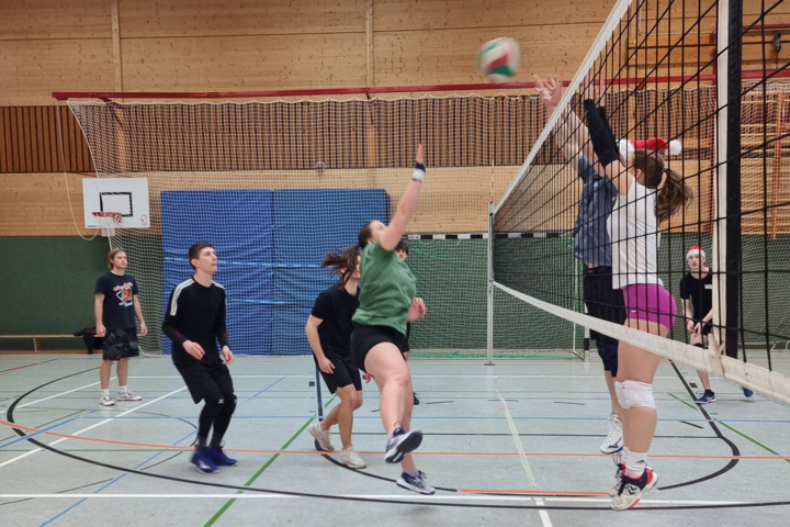 Junge Menschen beim Volleyballspiel in einer Turnhalle