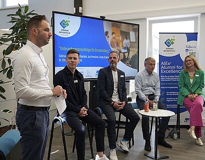 THWildau ZFT Nachfolge byJudithSchulz Auf dem Bild sind 5 Personen zu sehen, diese sitzen im Halbkreis vor einer elektrischen Tafel. Eine Person von ihnen steht, diese ist ganz links zu sehen und spricht in den Raum hinein.