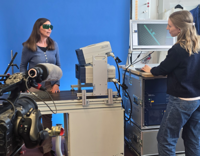 Imagevideo labor Eine Kamera im Vordergrund filmt eine Person an einem Pult