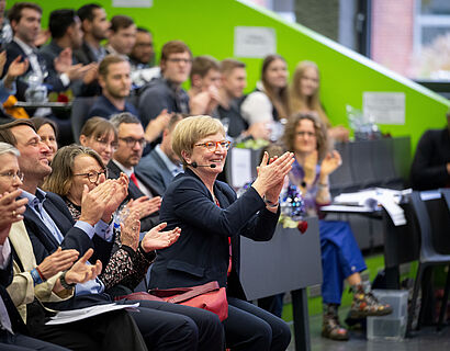 TH-Wildau-Präsidentin Prof. Ulrike Tippe sitzt im Publikum des Audimax bei der feierlichen Verabschiedung und applaudiert 