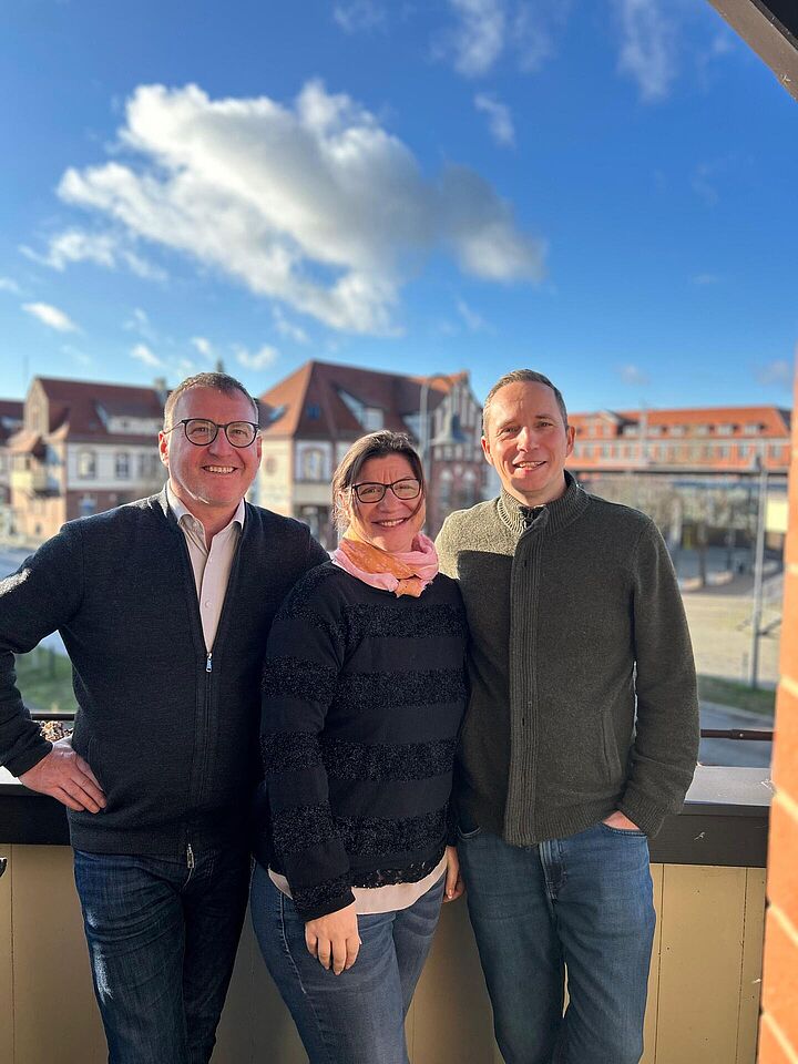 IMG 20250108 WA0000 Prof. Wolf, Prof. Lübbe und Susanne Trotzki vor ihre Aufnahme zu den TH THemen auf einem Balkon. Im Hintergund Wildau.