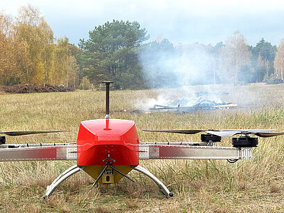 rote Drohne auf einem Feld mit Brandnestern