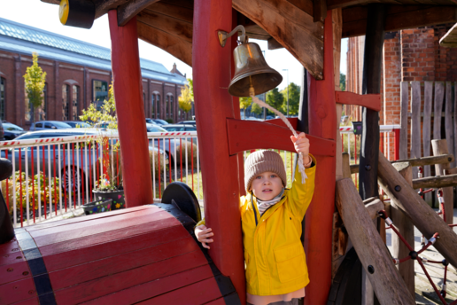 Kind klingelt auf einer Spieleisenbahn an einer Glocke