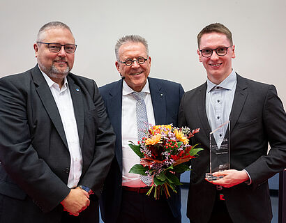 Prof. Andreas Hotes, Michael Halberstadt und ein prämierter Studierender bei einem Gruppenfoto