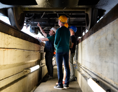 VST Exkursion Erkner historische S Bahn 2 Menschen stehen in einer Wartungsgrube unter einer S-Bahn