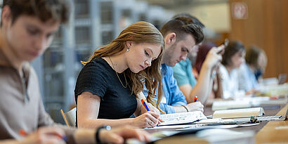 Bibliothek Studierende sitzen am Tisch in der Bibliothek und schauen in ihre Bücher