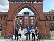 Zum Kick-Off-Meeting fand sich das hochschulübergreifende FASER-Projektteam an der Technischen Hochschule Brandenburg zusammen. Leute aus dem Projekt stehen vor einem Eingangstor der TH Brandenburg