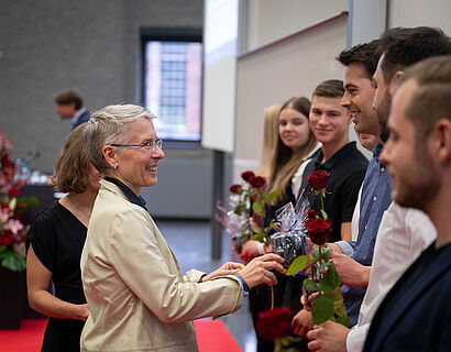 INW-Dekanin Prof. Heike Pospisil gratuliert einem Absolventen und übergibt ihm eine Rose bei der feierlichen Verabschiedung 2024