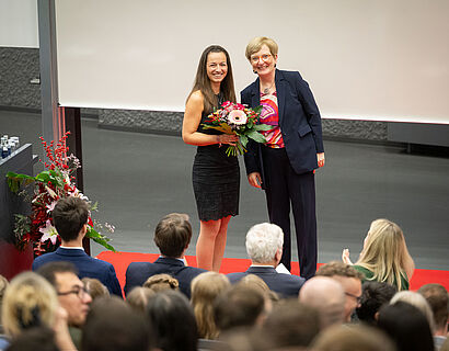 Prof. Ulrike Tippe gratuliert einer Absolventin mit einem Blumenstrauß